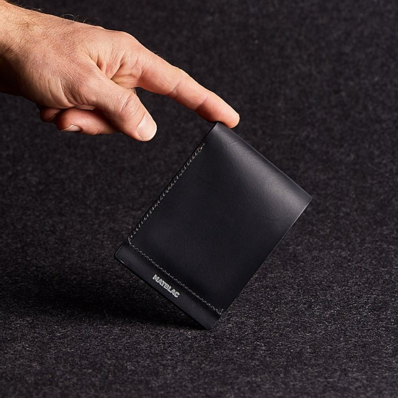 Close up of man balancing a minimalist black genuine leather magnetic wallet