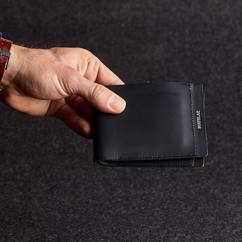 Close up of man holding a minimalist black genuine leather wallet