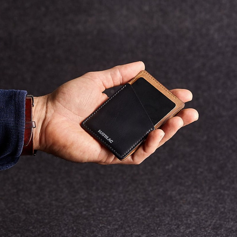 Close up of man holding a black and brown genuine leather quickdraw wallet on a grey background