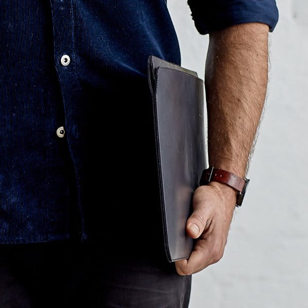 Front view of man holding minimalist black genuine leather laptop bag