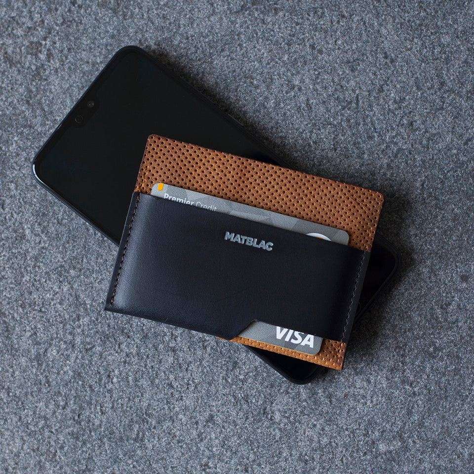 Close up of black and brown wallet lying on a phone against a grey background