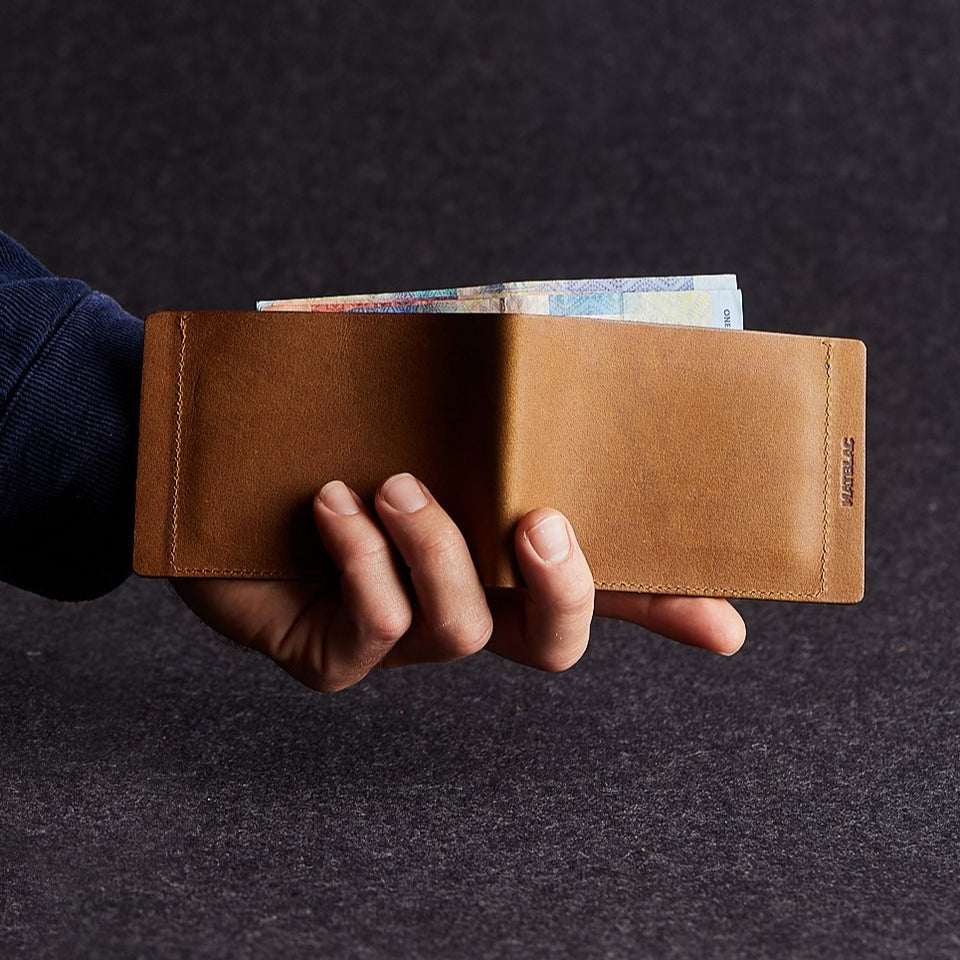 Close up of man holding open a minimalist brown genuine leather magnetic wallet