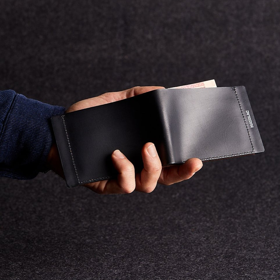 Close up of man holding open a minimalist black genuine leather magnetic wallet