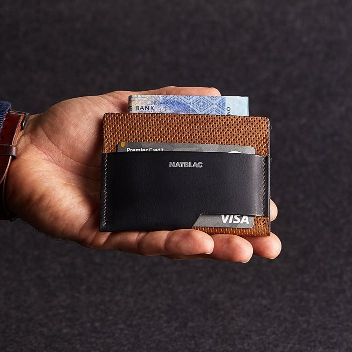 Close up of a man holding a black and brown genuine leather cash slip slim wallet on a grey background