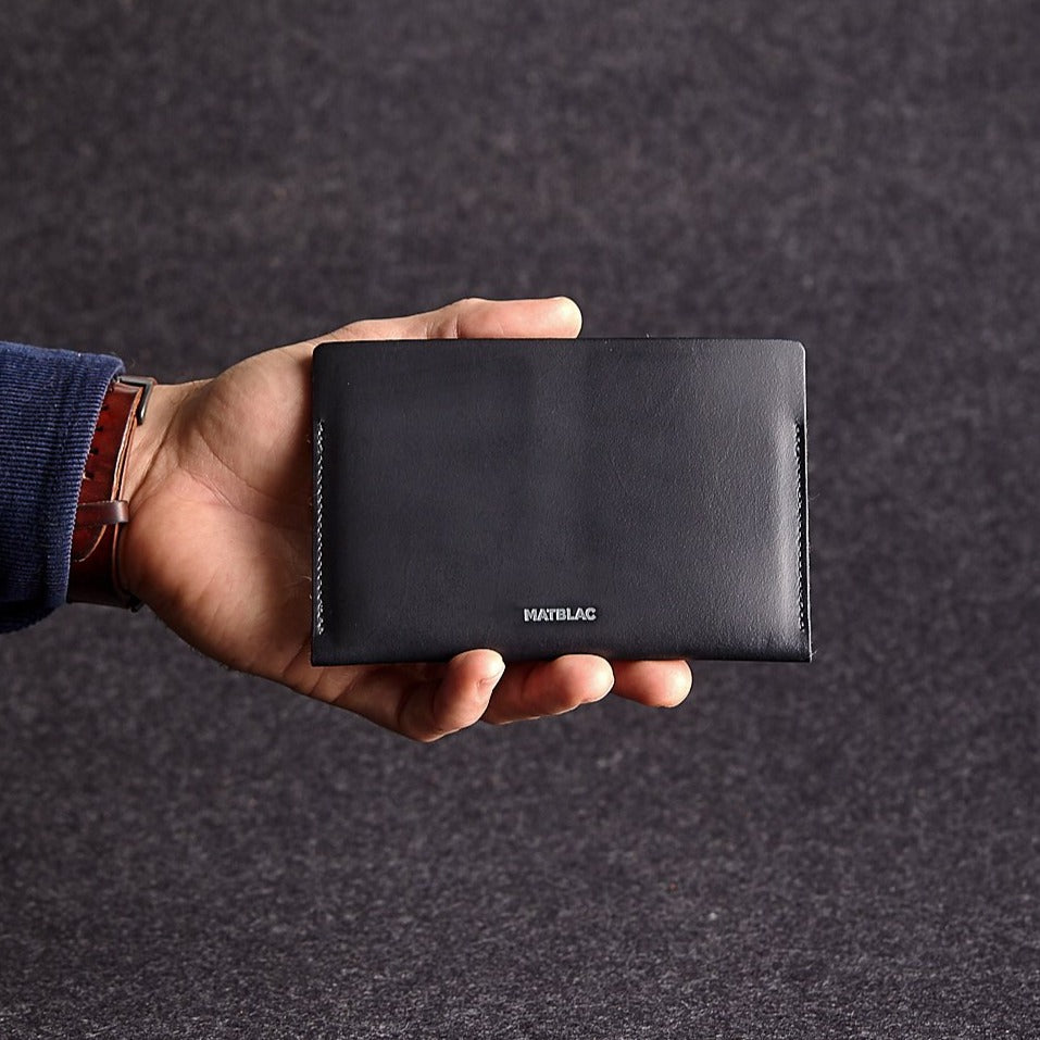 Man's hand holding black genuine leather passbook on grey felt background