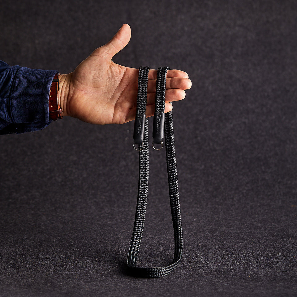Close up of man's hand holding black minimalist camera strap