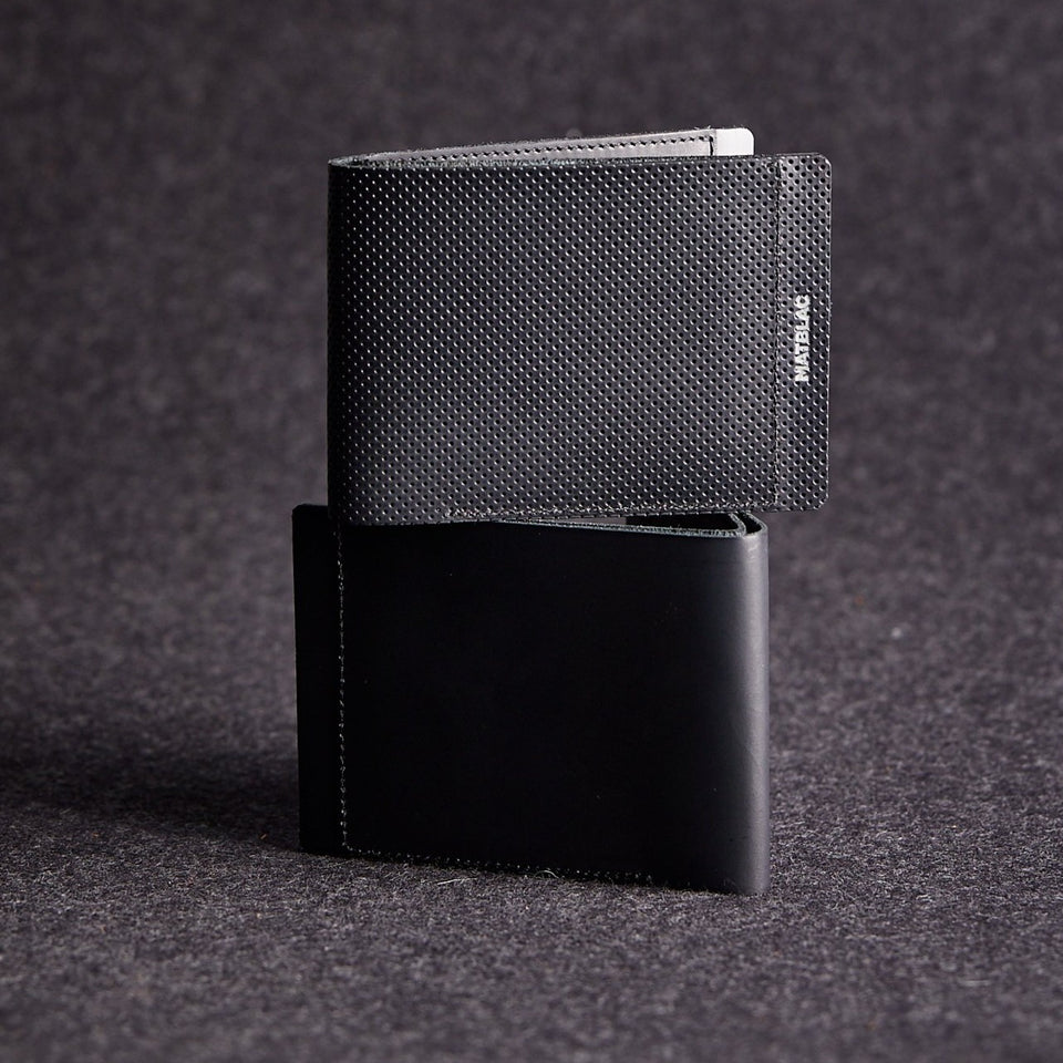 Two genuine leather wallets stacked on a grey felt background