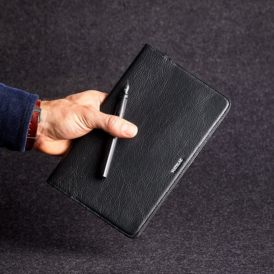 Close up of man's hand black genuine leather moleskine notebook jacket cover