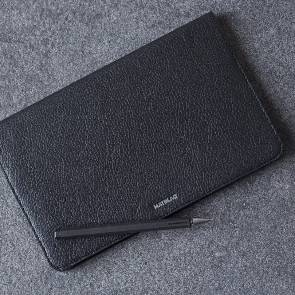 Black genuine leather moleskine notebook jacket cover and pen on grey background